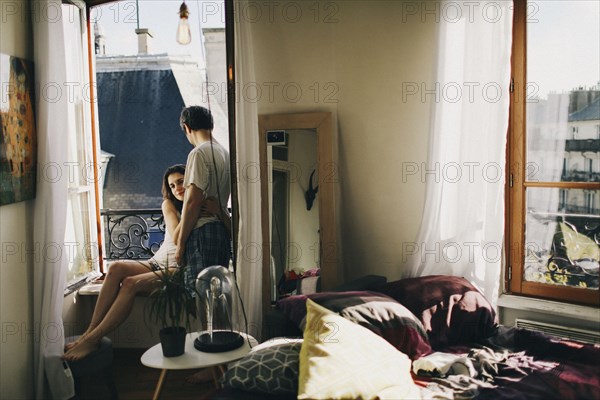 Caucasian couple hugging in apartment window