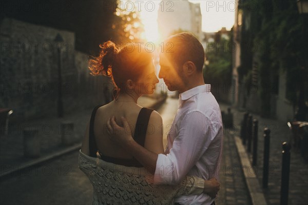 Caucasian couple hugging in city street at sunset