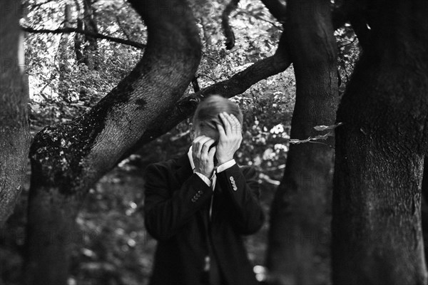 Caucasian businessman in forest with head in hands