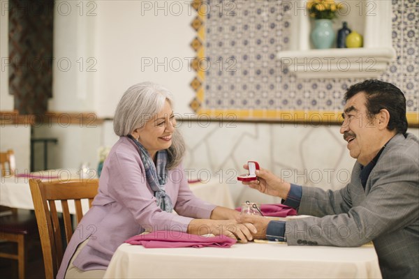 Older man proposing marriage to woman in restaurant