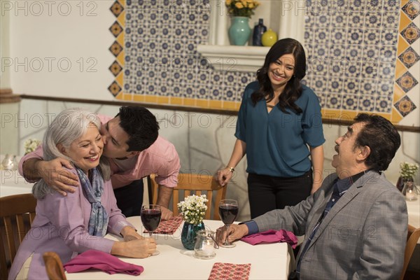 Younger couple greeting older couple in restaurant