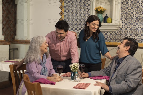 Younger couple greeting older couple in restaurant