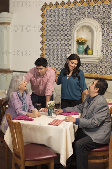 Younger couple greeting older couple in restaurant