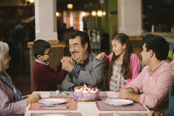 Family celebrating birthday or older man in restaurant