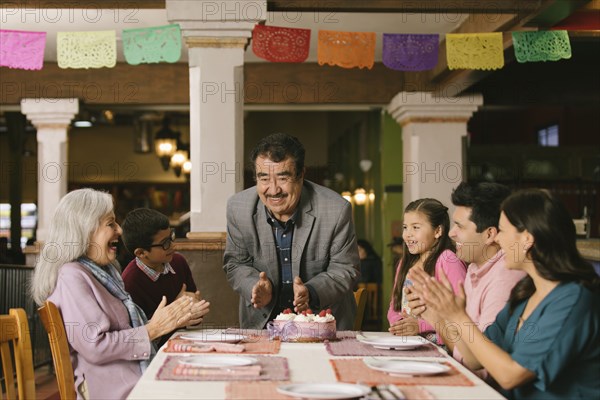 Family celebrating birthday of older man in restaurant