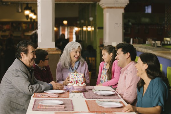 Family celebrating birthday of older woman in restaurant