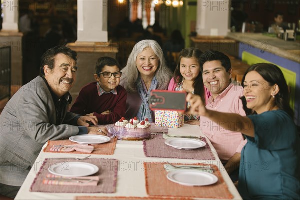 Family celebrating birthday posing for selfie in restaurant