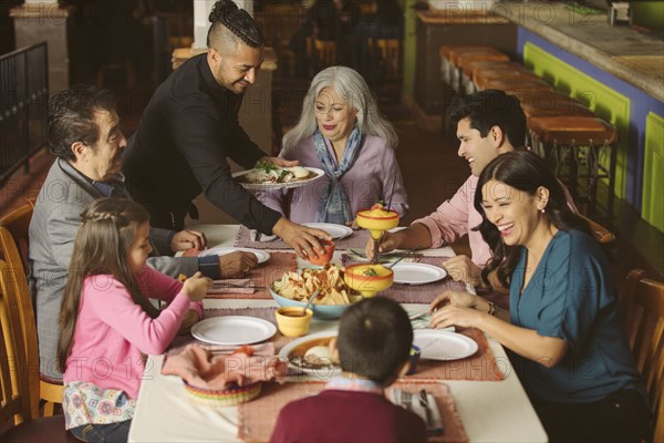 Waiter serving food to family in restaurant