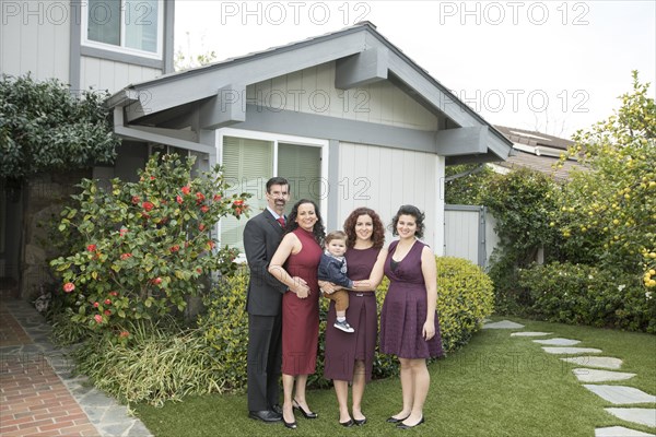 Multi-generation family posing near house