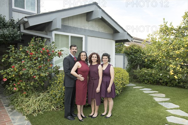 Parents and daughters posing near house