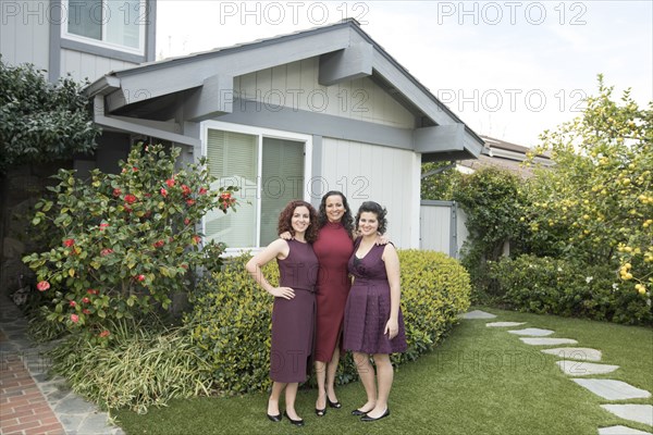 Mother and daughters posing near house