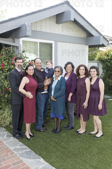 Multi-generation family posing near house