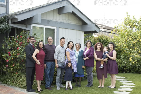 Multi-generation family posing near house