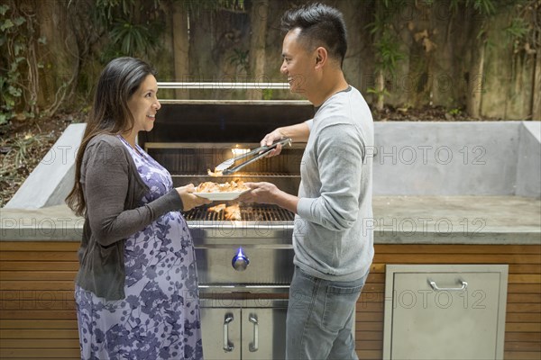 Man serving shrimp from grill to expectant mother