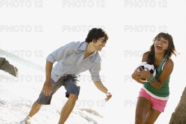 Couple playing with soccer ball on beach