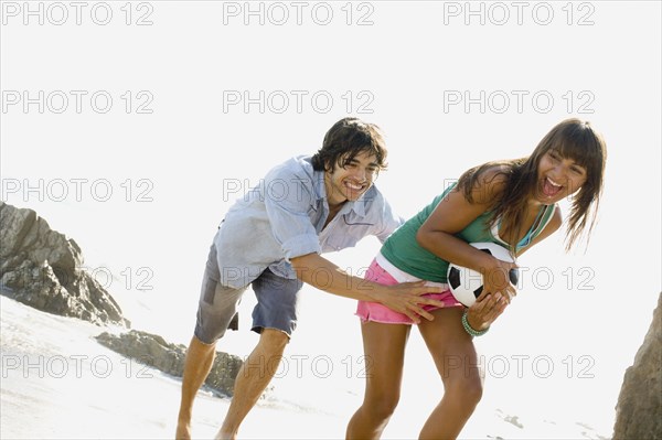 Couple playing with soccer ball on beach