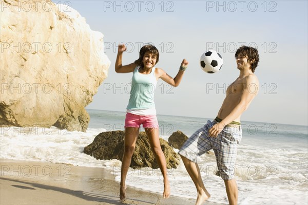 Couple playing with soccer ball on beach