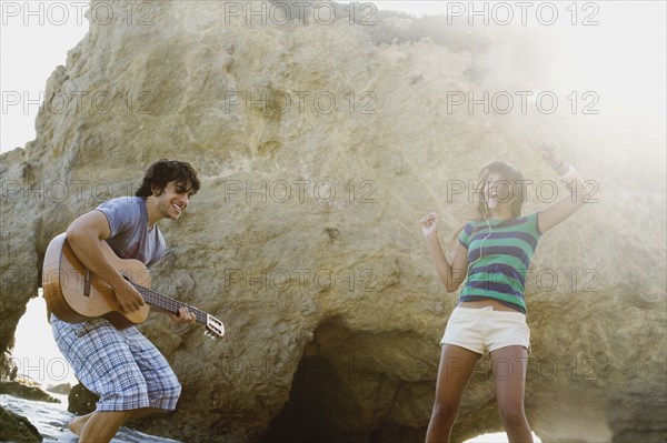 Man playing guitar for girlfriend on beach