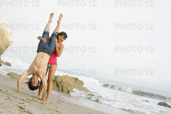 Woman supporting boyfriend doing handstand