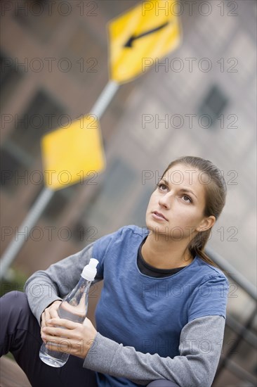 Hispanic woman drinking water in urban area