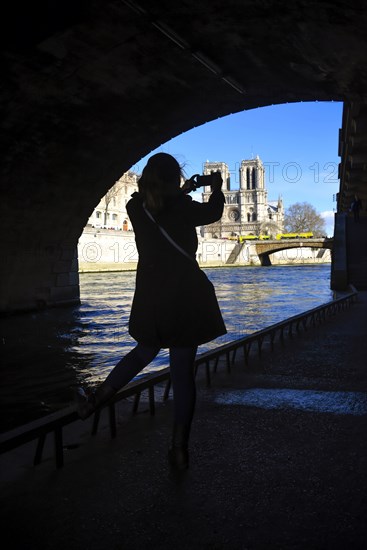 Girl under bridge photographing river