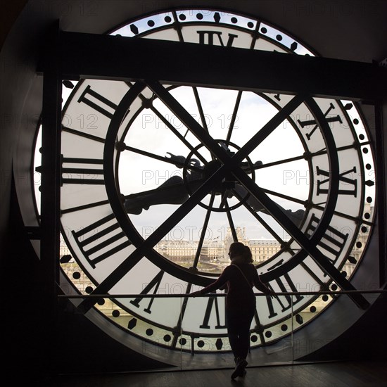 Girl looking at city from behind clock