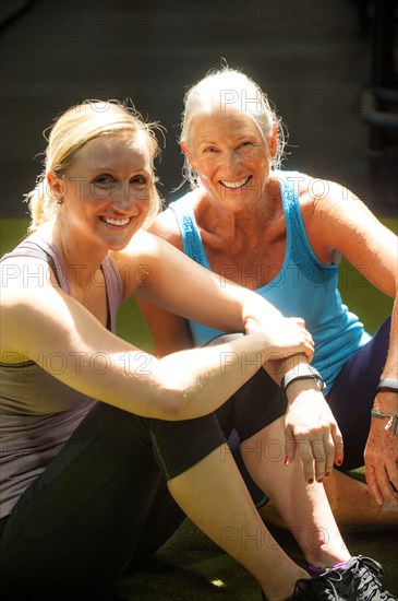 Smiling women resting on gymnasium floor