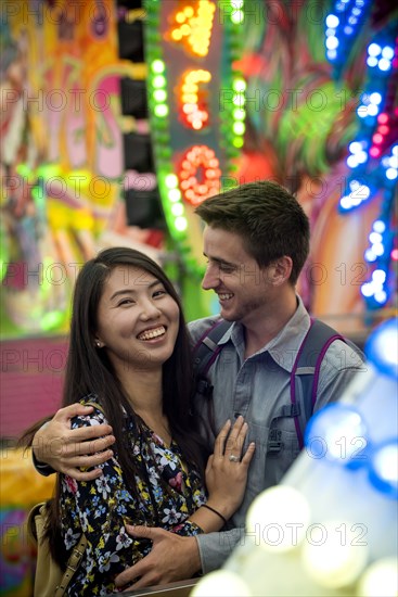 Smiling couple hugging in amusement park