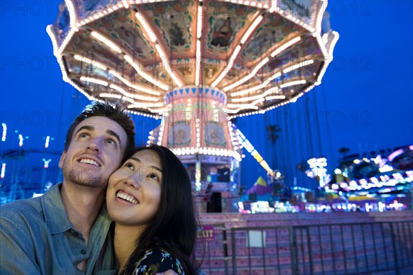 Smiling couple cheek to cheek in amusement park