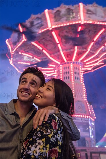 Smiling couple cheek to cheek in amusement park