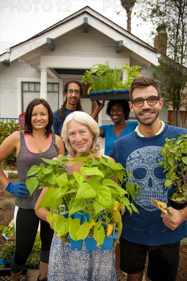 Portrait of neighbors holding plants near house