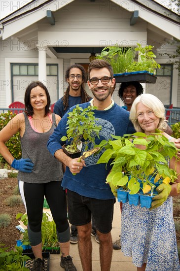 Portrait of neighbors holding plants near house