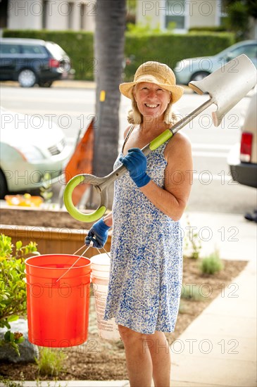 Portrait of smiling Caucasian woman holding shovel and buckets