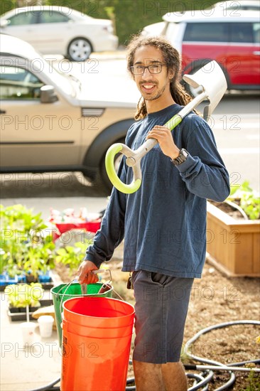 Portrait of smiling Black man holding shovel and buckets