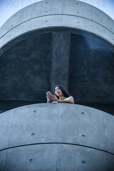 Low angle view of businesswoman on balcony texting on cell phone