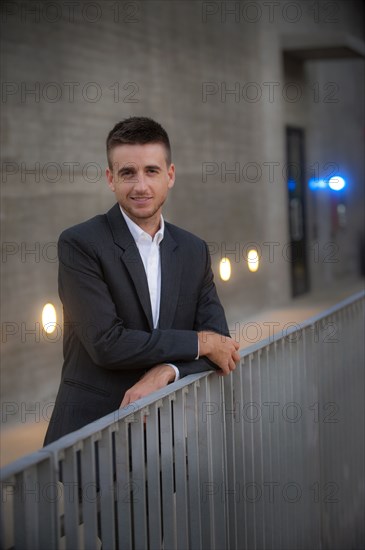 Portrait of smiling businessman leaning on railing