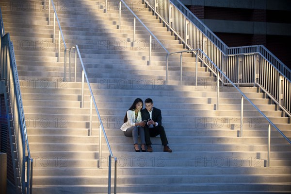 Couple sitting on staircase texting on cell phones