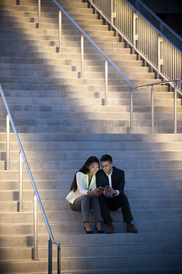 Couple sitting on staircase texting on cell phones