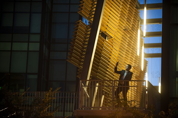 Businessman on balcony posing for cell phone selfie at night