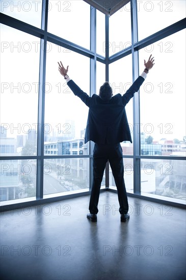 Hispanic businessman celebrating near window