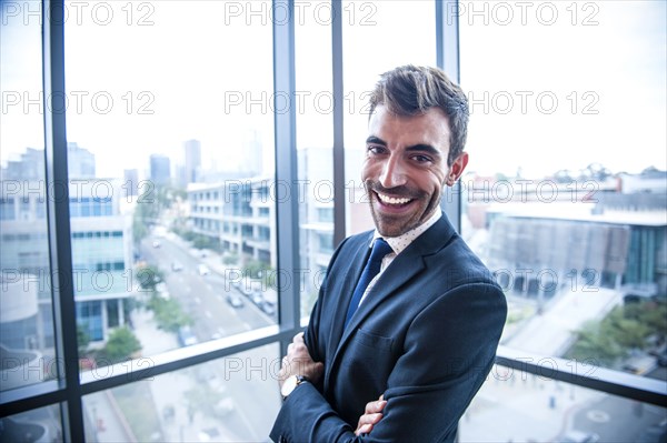 Portrait of smiling Hispanic businessman posing near window