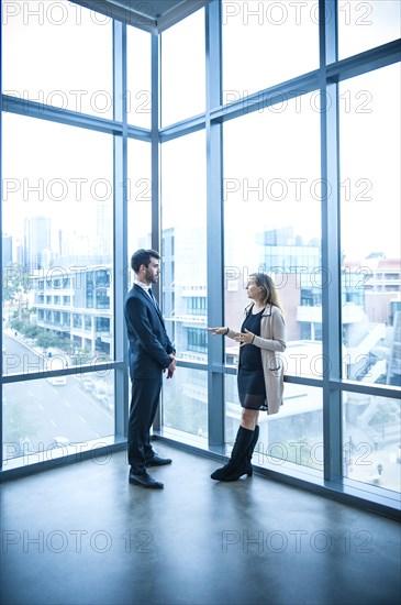 Businessman and businesswoman talking near window