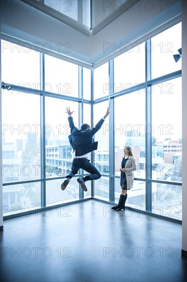 Businesswoman watching businessman celebrating near window