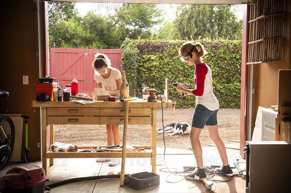 Sisters building birdhouse in garage