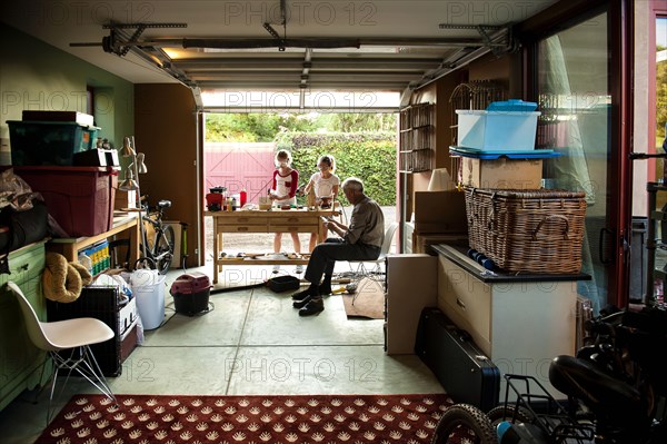 Grandfather watching granddaughters building birdhouse in garage