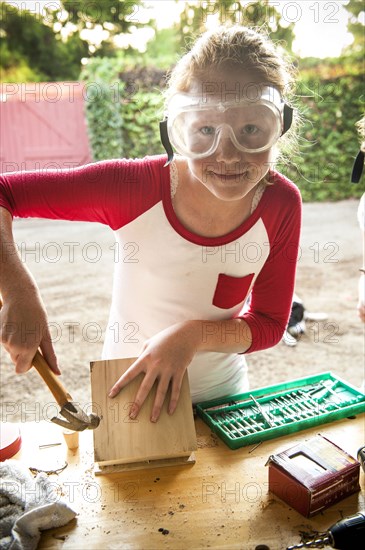 Girl hammering nails into birdhouse