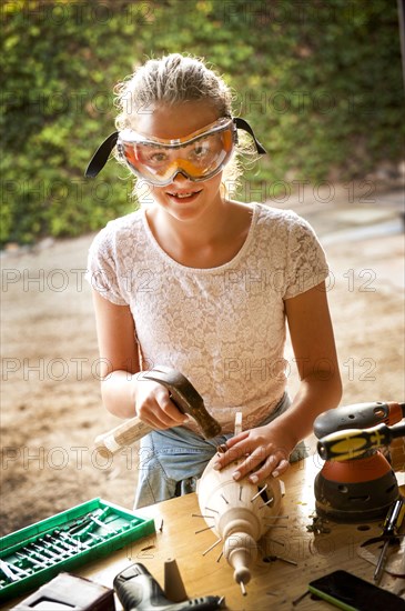 Caucasian girl hammering nails into birdhouse