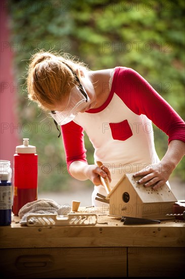 Girl hammering nails into birdhouse