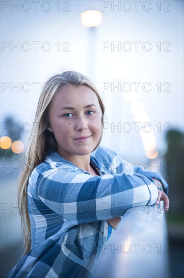 Portrait of smiling Caucasian teenage girl leaning on railing