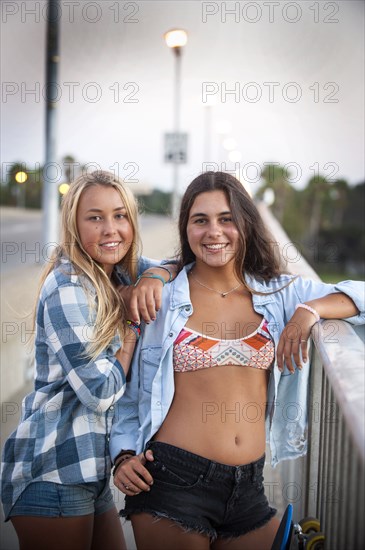Portrait of smiling teenage girls leaning on railing